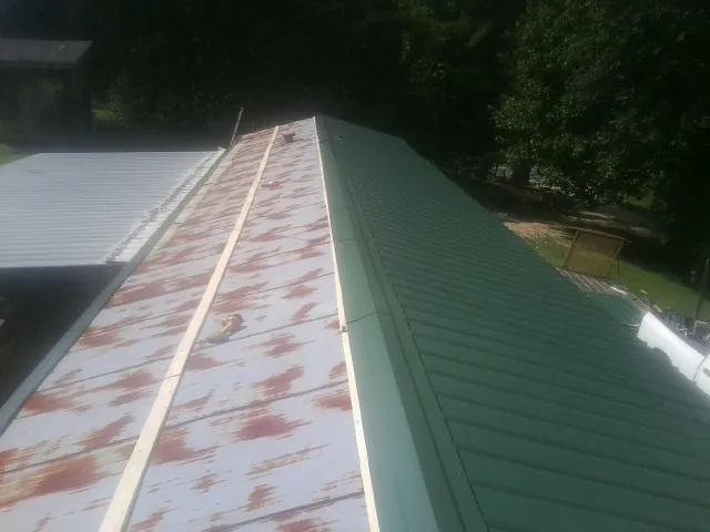 Old rusted panels beside newly installed green metal roofing — Wind Damage Roof Repair by Roofing Brothers in Bridgewater
